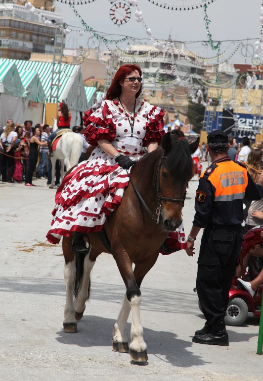 a lady in red and white dress riding on a brown horse