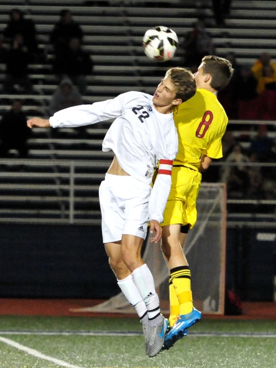 soccer player in red attempting to block another player in yellow