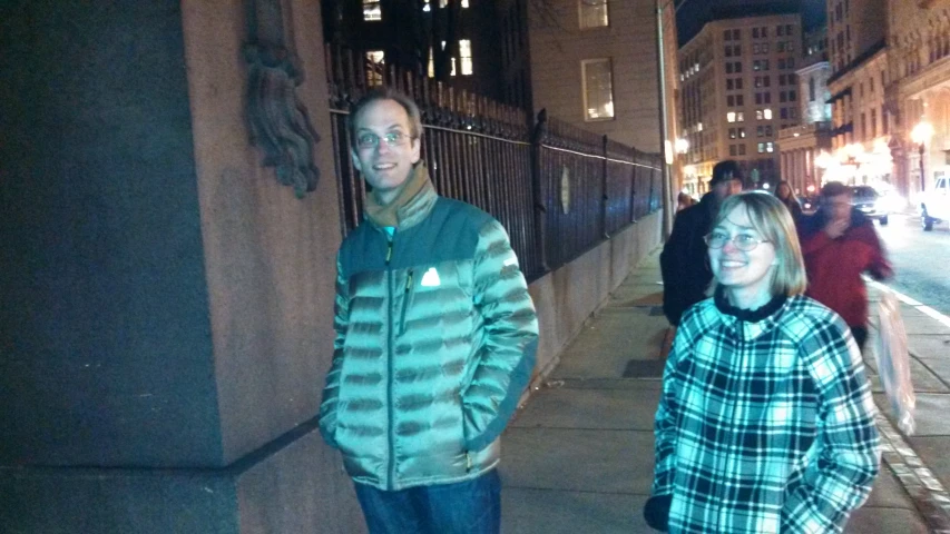 man and woman standing near the curb on a busy street at night