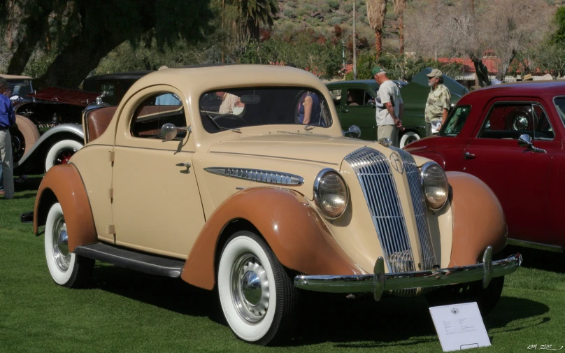 a tan and tan classic car on display at an antique auto show