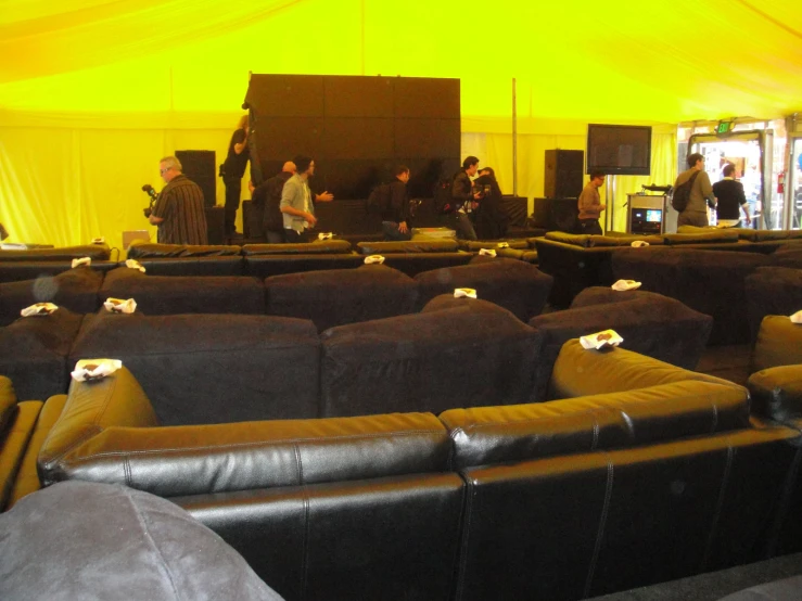many leather sofas with white flower petals in the center of a large tented auditorium