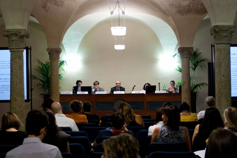 two people speaking at a podium in front of a crowd of people