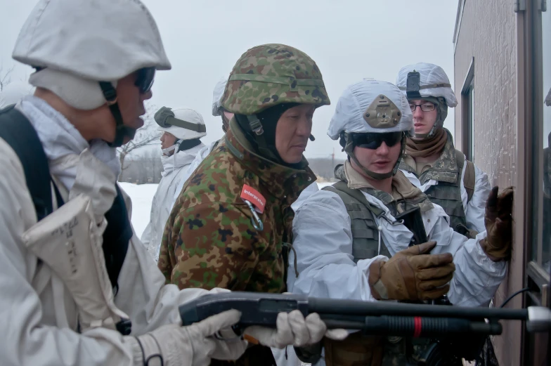 soldiers gather around in snow - covered area and have their weapons raised