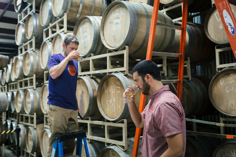 two men standing in front of some wine barrels