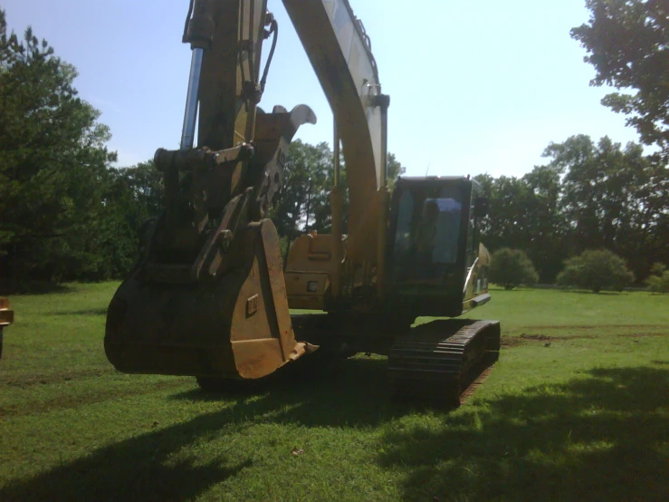 a construction vehicle sits on the grass in the open field