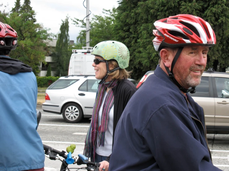 three people on bicycles with helmets are waiting at an intersection