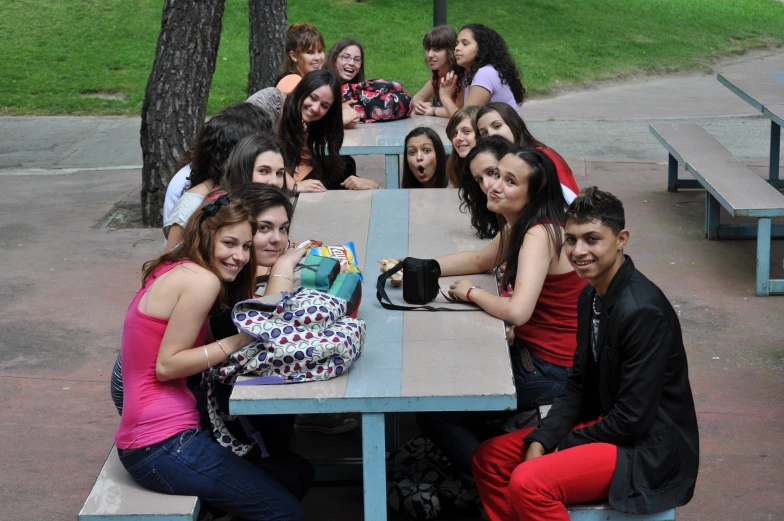 the people are sitting at a picnic table together