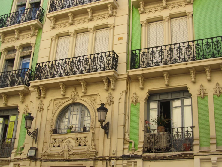 an outside view of a green and yellow building with balconies and a clock