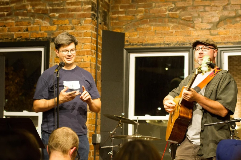 two men standing on stage with musical instruments and microphones