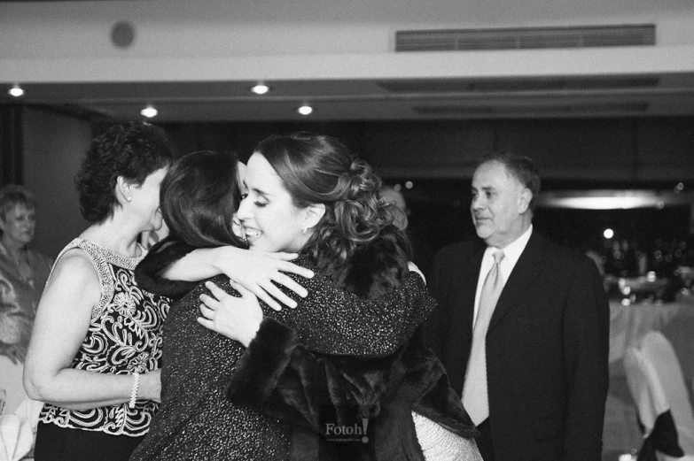 a young woman hugging another young woman at a formal function