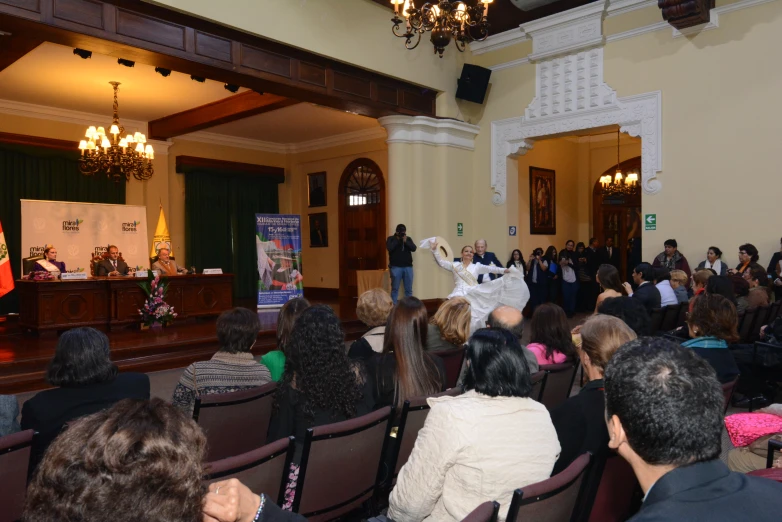 a crowd watches a man on stage while others watch from the side