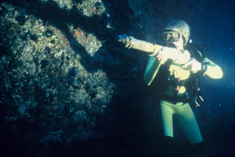 a scuba with a flashlight and in wetsuit looking at soing