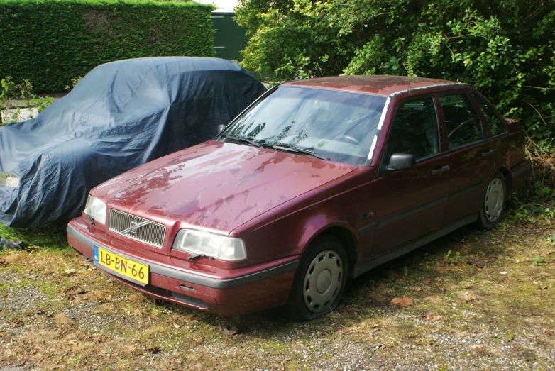 a car is covered in a tarp near trees