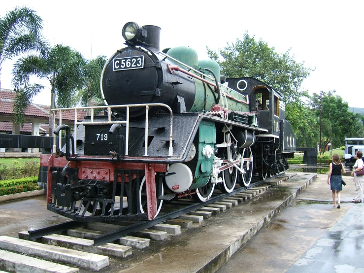 a black and white train engine next to people and trees