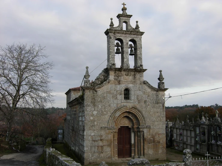 old stone building with tall bell towers sitting next to graveyard