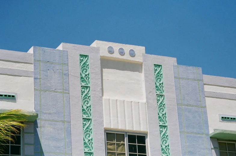 a tall white building with decorative windows and a green plant in the window