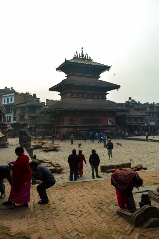 people are standing in a square near a pagoda