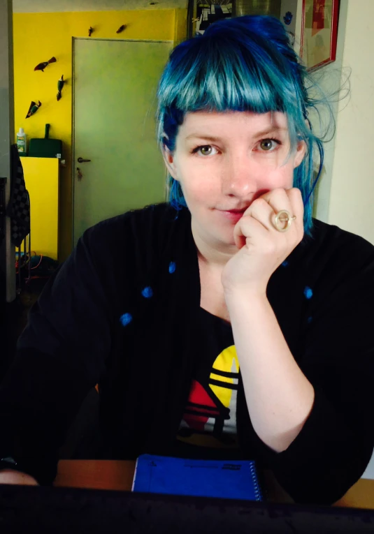 woman with blue hair sitting at a table