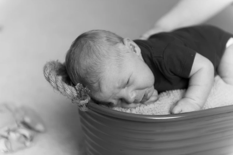 the small baby is curled up in a tub