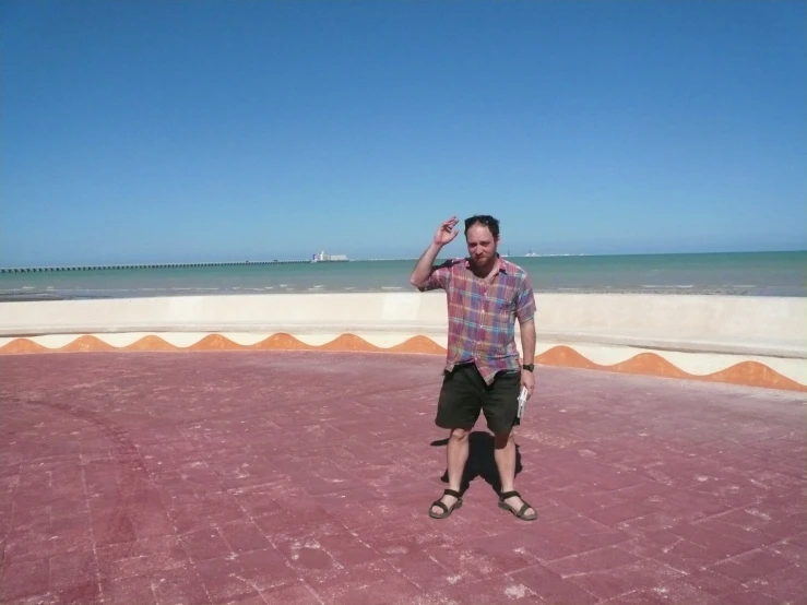 a man standing near the beach, making a hand gesture