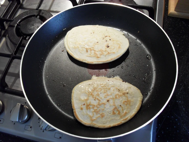 pancakes being cooked in a frying pan on the stove top