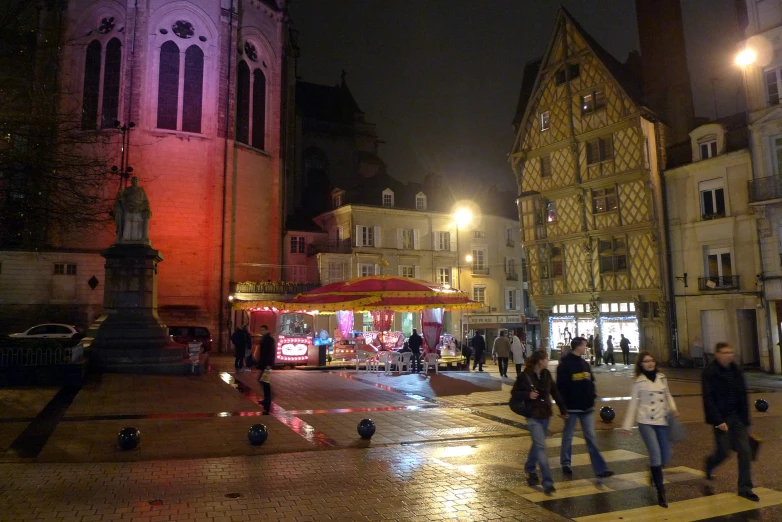 people walking around a cobblestone road during the night