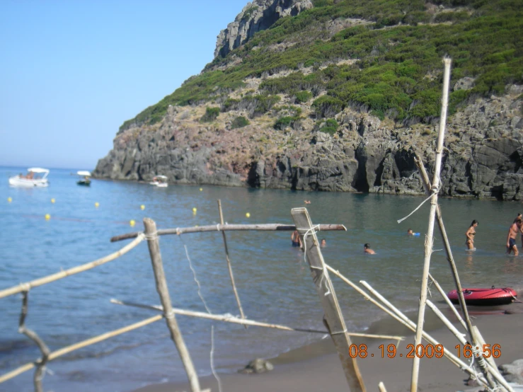 people in the water on the beach near a mountain