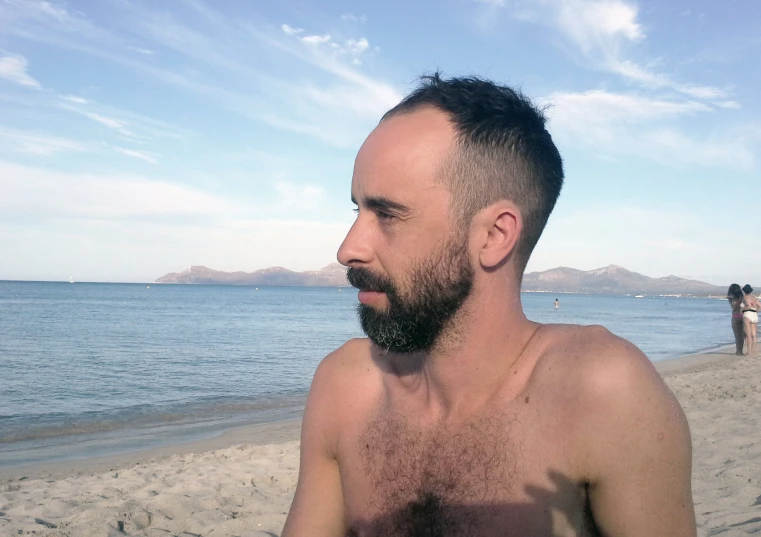 a man on the beach standing with the water in the background