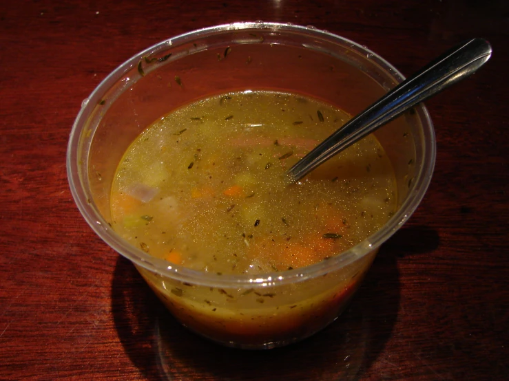 soup with vegetables in a plastic cup and two spoons