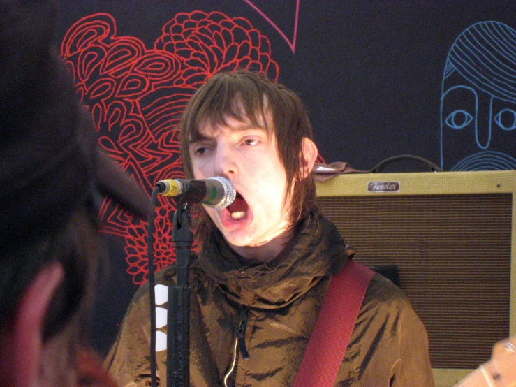 a male singing into a microphone with a guitar in the foreground