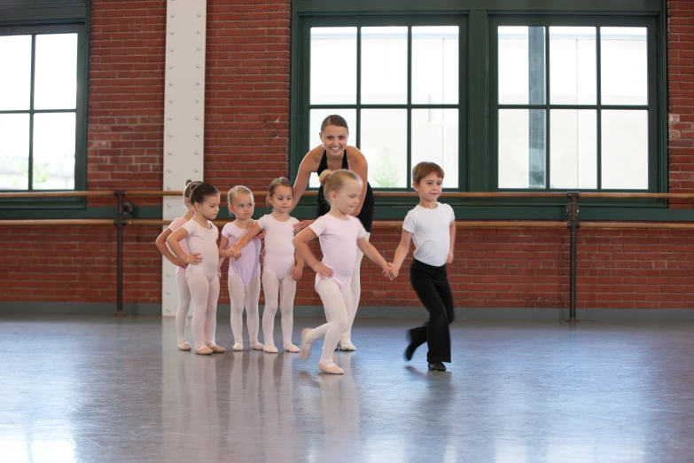 a woman standing next to children with one ballerina