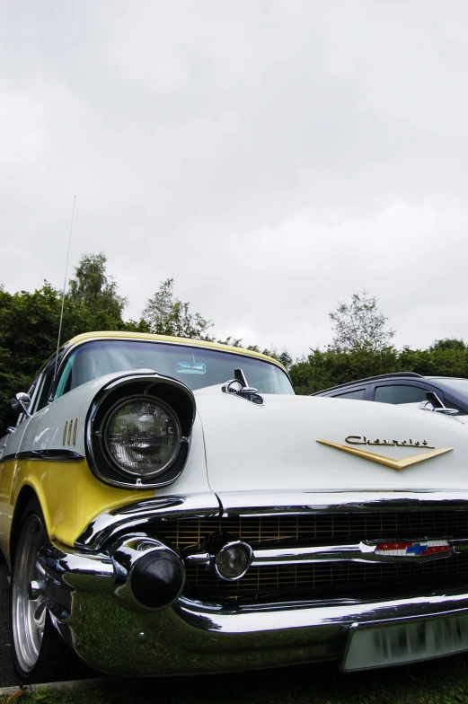 an old - fashioned car parked in grass on a cloudy day