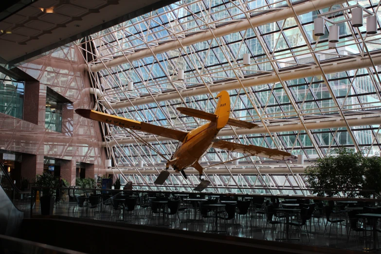 a airplane flying through the sky in an indoor atrium