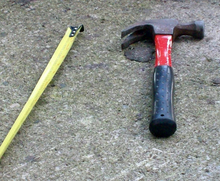 the hammer is laying in the sand near a yellow handle