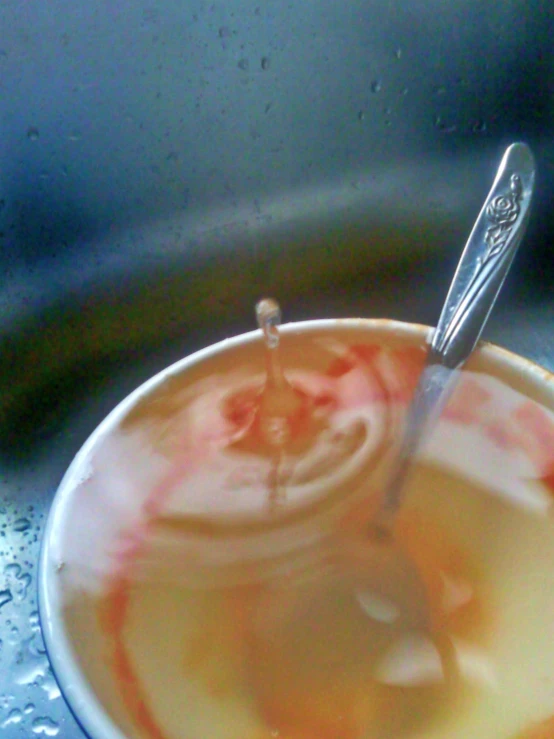 liquid in cup with spoon inside bowl with water
