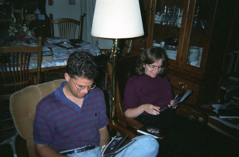 two people sitting on a chair looking at papers