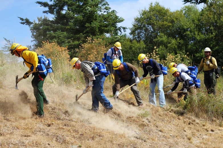 many people wearing helmets standing around digging in the grass