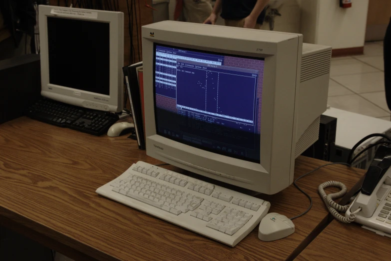 an old computer with the screens pulled out, beside two other computers