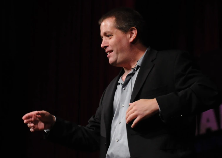 a man in suit stands while talking and gesturing