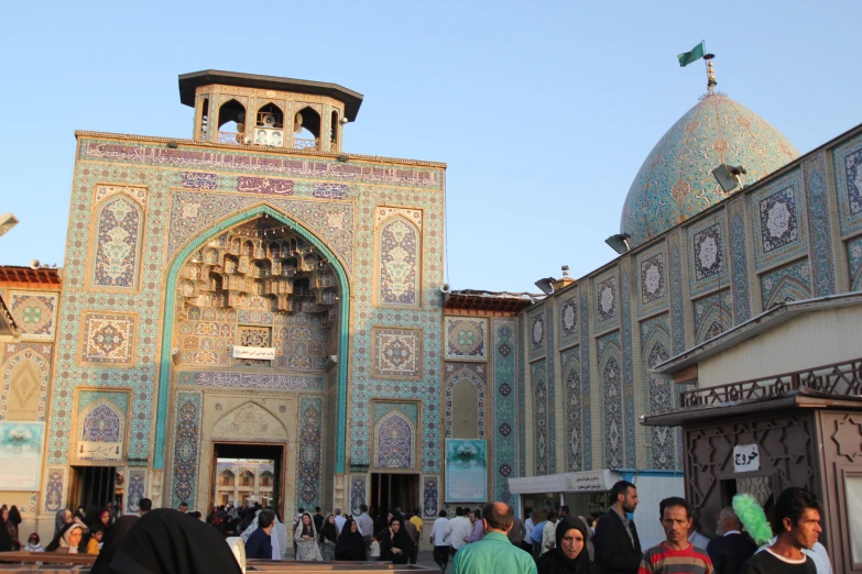 several people are walking past a building with intricate tiles