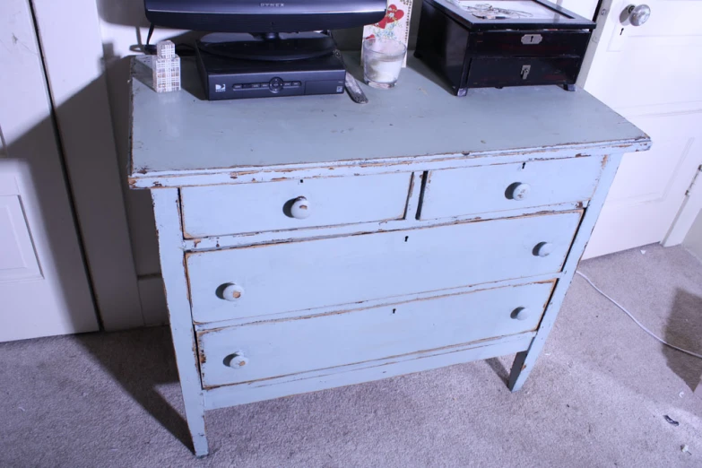 an old blue dresser has two televisions on top