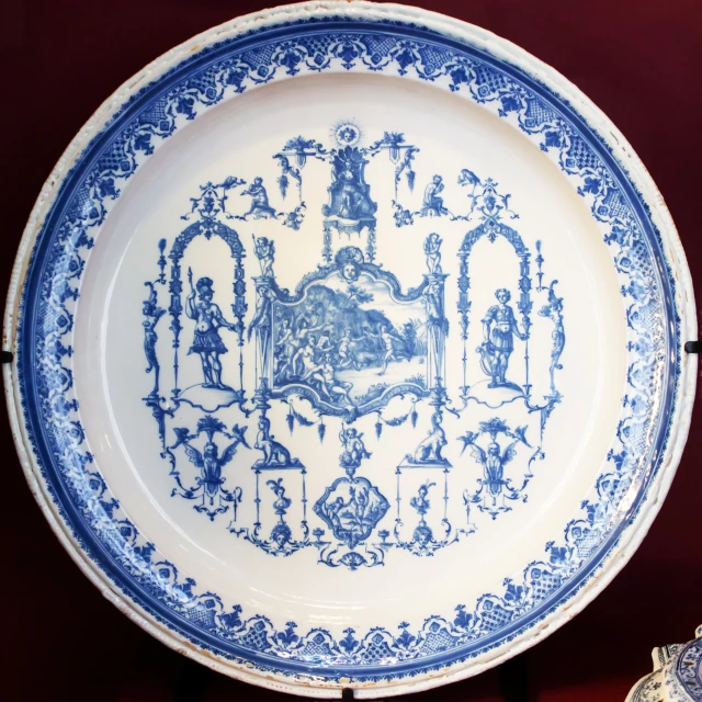 a blue and white plate on display next to a smaller vase