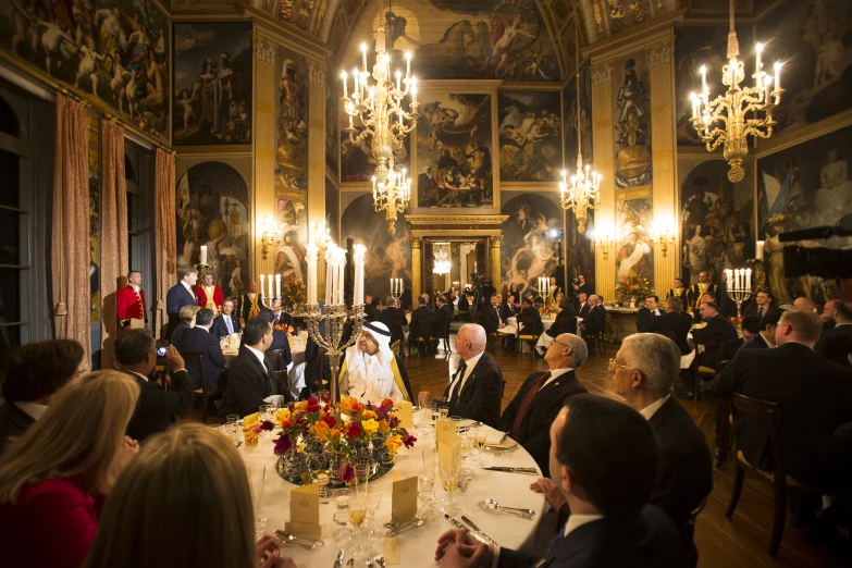 a big room with tables, chandeliers and a couple seated at the table