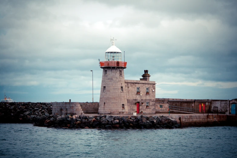 a lighthouse is on top of a wall beside the water