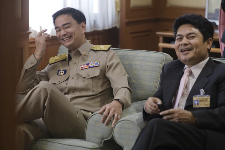 the two men are sitting together smiling and talking