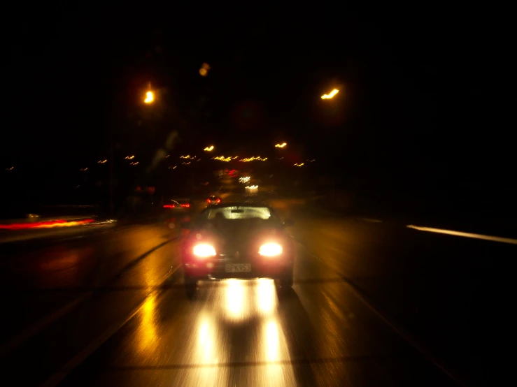 a car driving down a wet highway at night