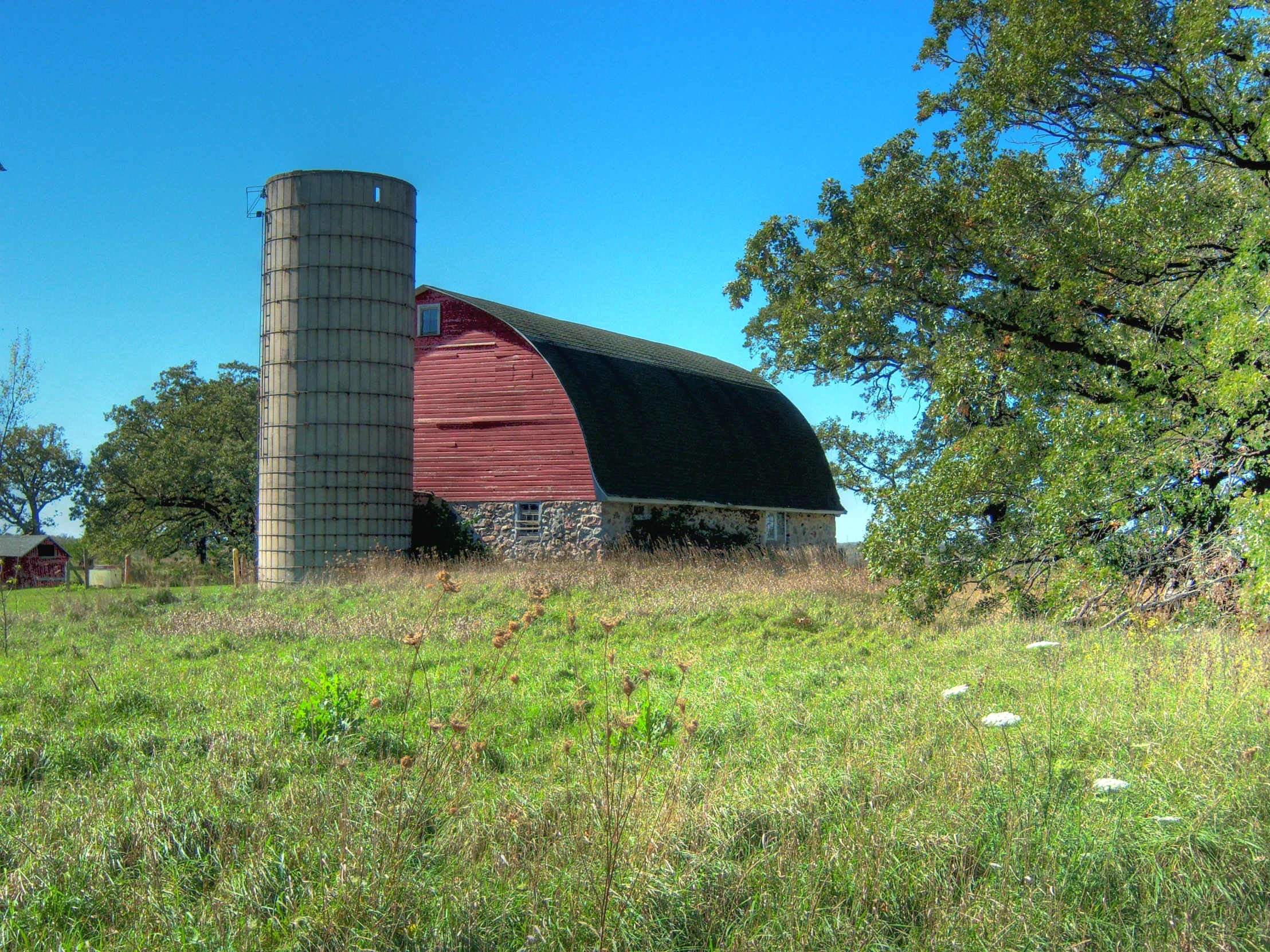 a red barn sits in the middle of the field