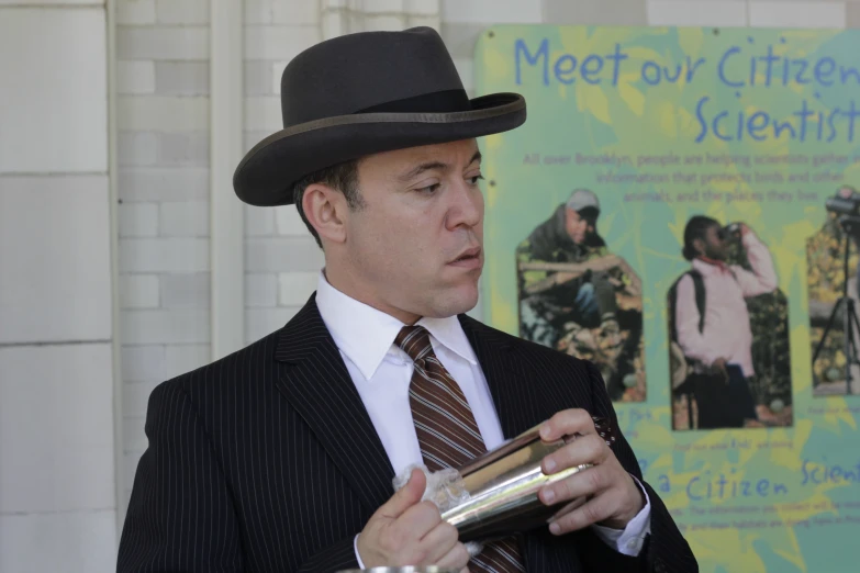 a man wearing a black suit and tie holding a gold cup