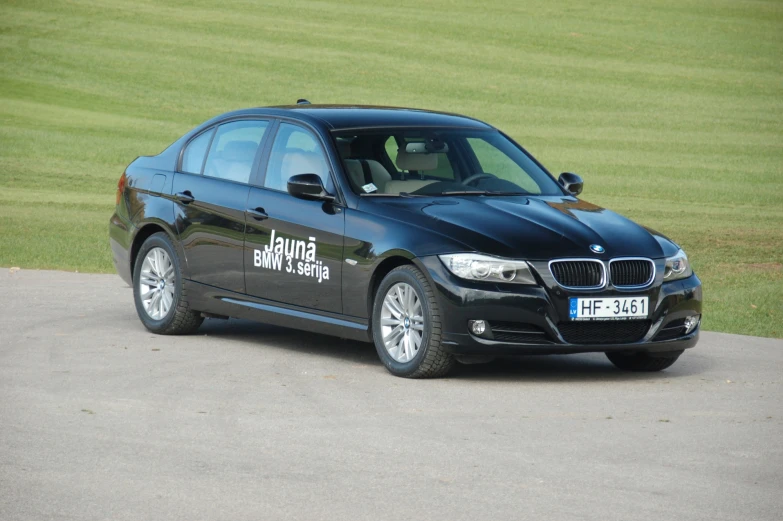 the bmw car has a large windshield and is parked on a parking lot