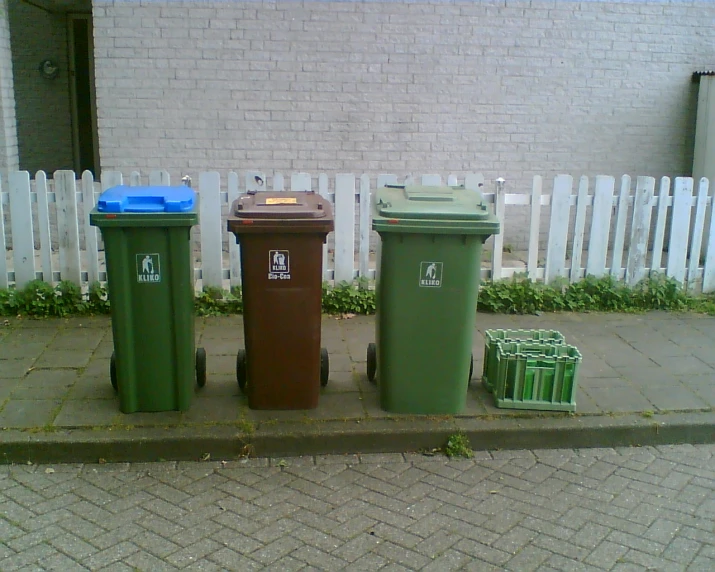 a brick wall next to some green and brown trash cans